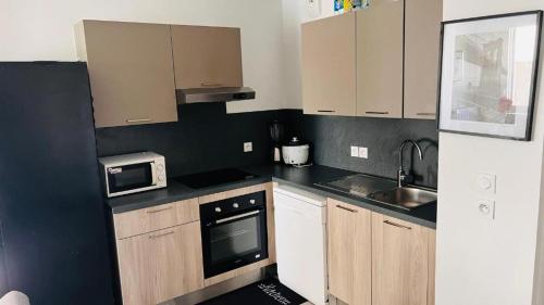 Elle comprend une petite cuisine avec des placards en bois et un évier. dans l'établissement Appartement -Résidence de Standing avec Terrasse, à Lyon