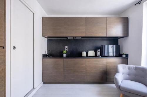 une cuisine avec des placards en bois et une chaise bleue dans l'établissement Havre de Luxe au Pied de Montmartre, à Paris