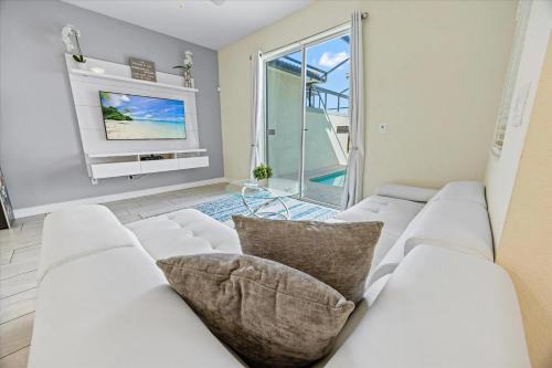 a white living room with a white couch and a tv at La Casista in Orlando