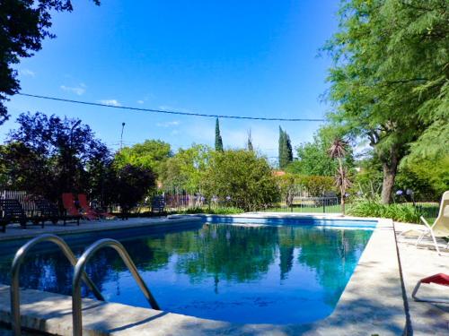 a swimming pool with blue water in a park at Hostal La Merced in Villa General Belgrano