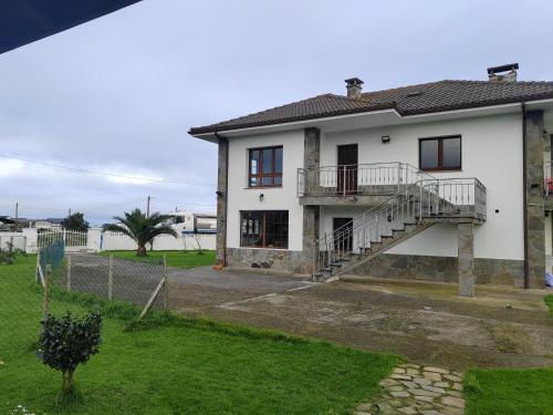 a white house with a staircase and a yard at El Rancho Busto - Luarca in Busto