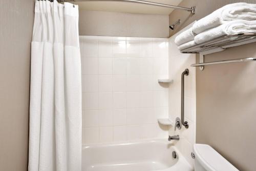 a bathroom with a white tub and a white shower curtain at SpringHill Suites Thatcher in Thatcher
