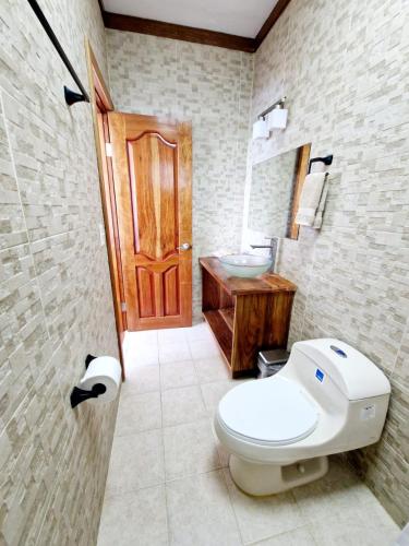 a bathroom with a toilet and a sink and a door at Chango's Apartments in Bocas del Toro