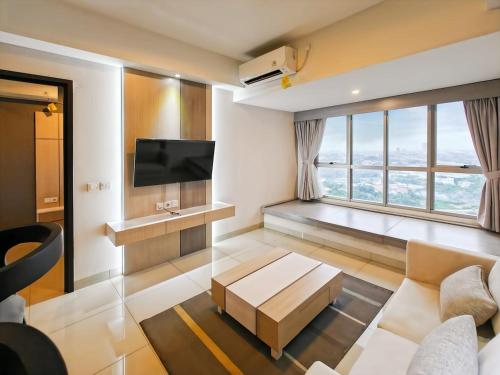 a living room with a couch and a tv at Newly 1BR Apt Cikarang with Pool, Gym & Wi-Fi by 2ndHome in Leuweungmalang
