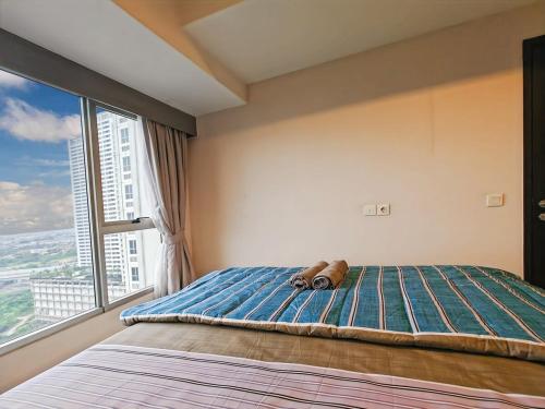 a teddy bear laying on a bed with a window at Newly 1BR Apt Cikarang with Pool, Gym & Wi-Fi by 2ndHome in Leuweungmalang