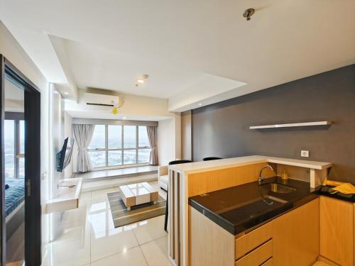 a kitchen with a sink and a living room at Newly 1BR Apt Cikarang with Pool, Gym & Wi-Fi by 2ndHome in Leuweungmalang