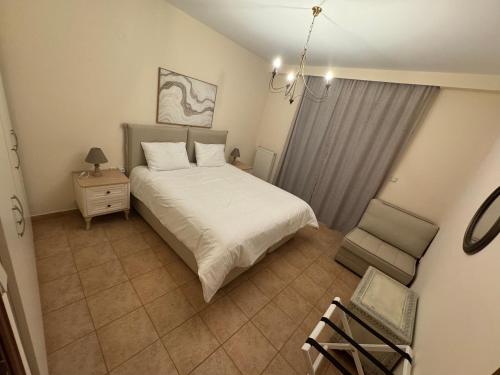 een slaapkamer met een wit bed en een stoel bij Villa Reina 2 in Alexandroupoli