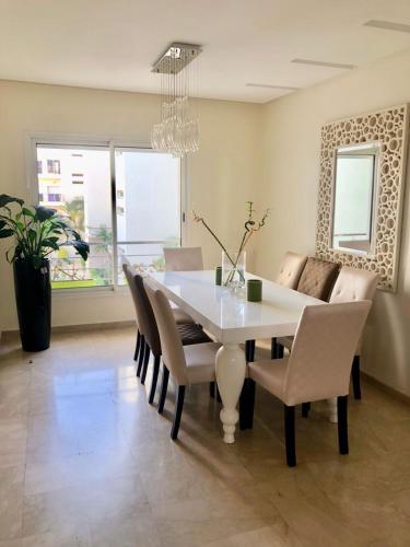 a dining room with a white table and chairs at Luxueux appartement Bay view dans une résidence avec magnifique jardin in Casablanca