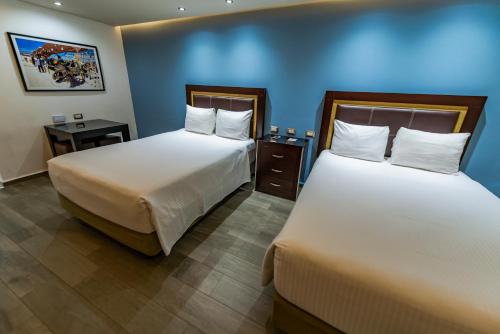 two beds in a room with blue walls at Quinta Dorada Hotel & Suites in Saltillo
