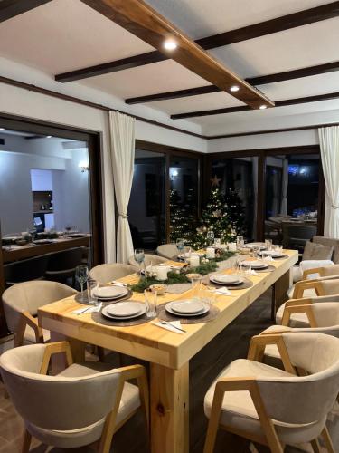 una larga mesa de madera con sillas y un árbol de Navidad en ВИЛА ЯНА Villa Yana, en Presoka