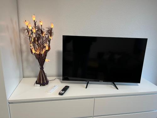 a tv and a vase with candles on a table at Studio an der Elbe mit Balkon, Küche und Netflix in Dresden
