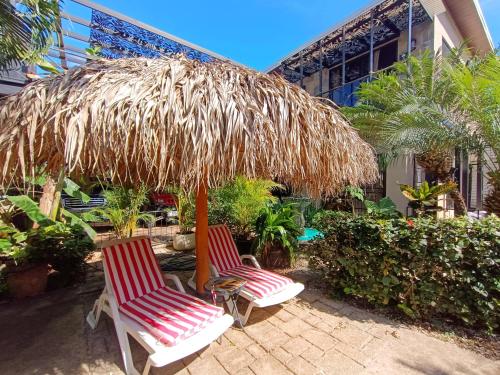 two chairs under a straw umbrella on a patio at Suite Dream Blue in Tamarindo