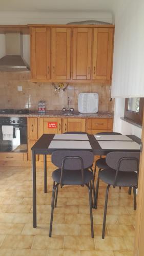 a kitchen with a table and four chairs in it at Na Rota - Casa de Praia in Zambujeira do Mar