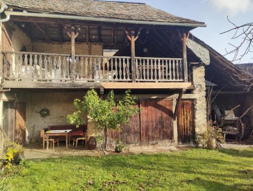a house with a deck and a table on the porch at Aile de la Maison de Chouliou in Balaguères