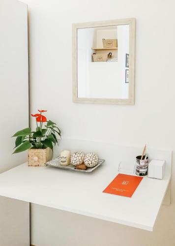a white shelf with a mirror and a plant on it at HELIOS ApArt Hotel - DeLuxe Residence, close to the city CENTER in Timişoara