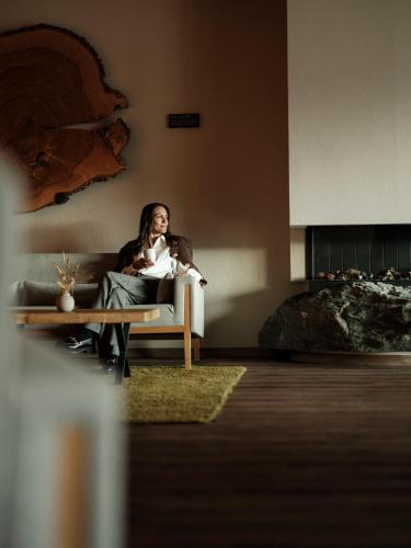 a woman sitting on a couch in a living room at SPA & Naturhotel Outside in Matrei in Osttirol