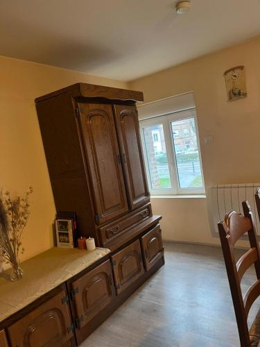 a large wooden cabinet in a kitchen with a window at Appartement calme, frais à louer, nouvellement repeint, emplacement stratégique, proche de toutes commodités, de l'autoroute, valenciennes, lille, Belgique, wifi, Netflix, parking Gratuits in Raismes