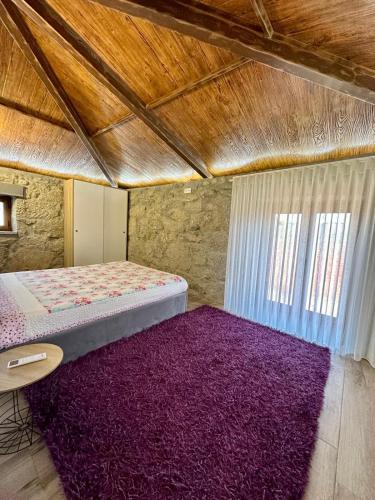 a bedroom with a bed and a purple rug at Quinta da Cachada in Lousada