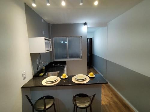 eine Küche mit einer Theke mit Stühlen und Tellern darauf in der Unterkunft Apartamento aconchegante no centro de São Lourenço 700m do Parque das Águas in São Lourenço