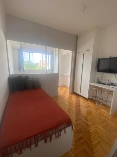 Un dormitorio con una cama, un escritorio y un televisor. en Studio ótima localização, en Foz do Iguaçu