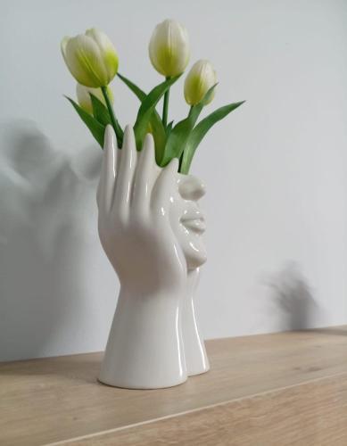 a white vase with a hand holding a bunch of flowers at Blue House in Pizzo