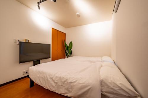 a bedroom with a bed and a flat screen tv at Willow Heim in Kawaguchi