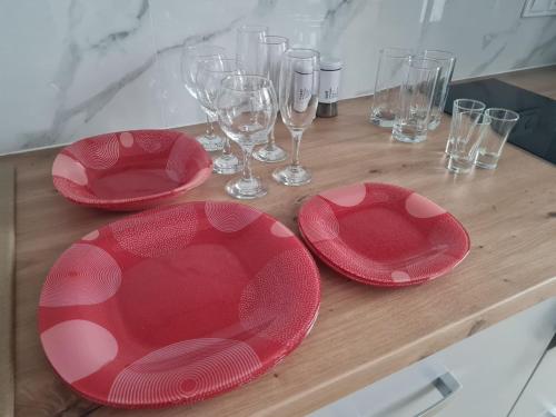 three red plates and wine glasses on a wooden table at ApartPlus - Затишні апартаменти in Dnipro