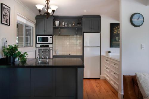 a kitchen with black cabinets and a white refrigerator at Margies on Mt Franklin 8 minutes from Daylesford in Hepburn Springs