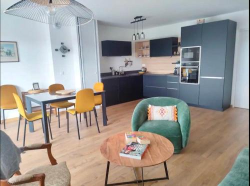Il comprend un salon et une cuisine avec une table et des chaises. dans l'établissement Magnifique appartement climatisé 70 m2, Grande terrasse 42 m2, classé 4 étoiles, à Andernos-les-Bains