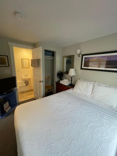 a bedroom with a large white bed and a bathroom at Elmwood Motor Court in Old Orchard Beach