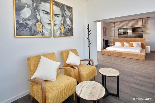a living room with two chairs and a bed at אגמוניה in Menaẖemya
