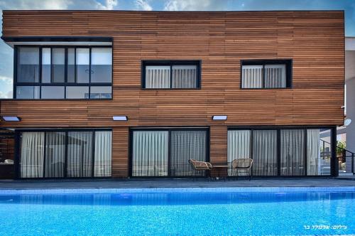 a building with a table and chairs next to a pool at אגמוניה in Menaẖemya