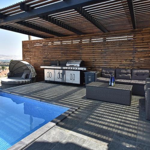 a patio with a grill and a swimming pool at אגמוניה in Menaẖemya
