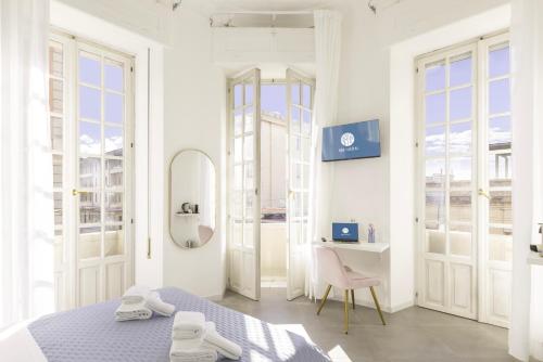 a bedroom with a bed and a desk and windows at Maddalena Rooms - Eja Sardinia in Cagliari