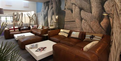 a living room with brown leather couches and tables at ibis Styles Quiberon Centre in Quiberon