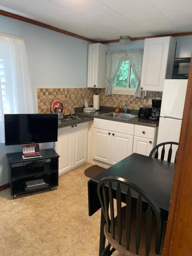 a kitchen with white cabinets and a black table and chairs at Elmwood Motor Court in Old Orchard Beach