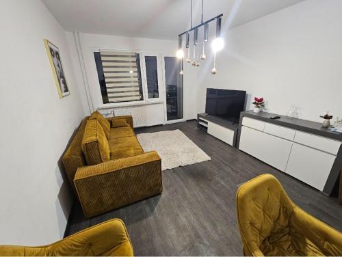 a living room with a couch and chairs and a kitchen at Apartament Marcello Teczowe 8B 8 in Dzierżoniów