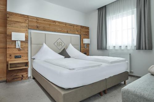 a bedroom with a large bed with white sheets at Rainerhof in Flachau
