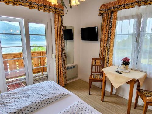 a bedroom with a bed and a table and a window at Pension Sedlak in Millstatt