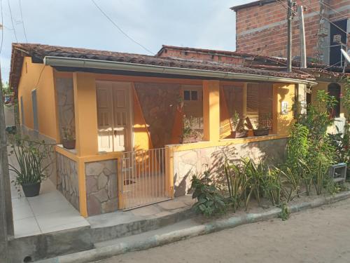una pequeña casa con porche y puerta en Casa Bacana Boipeba, en Isla de Boipeba