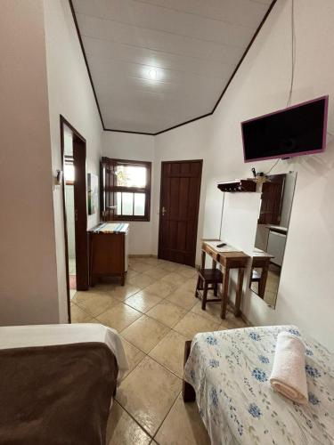 a room with two beds and a desk and a television at Cantinho Centro Histórico in Paraty