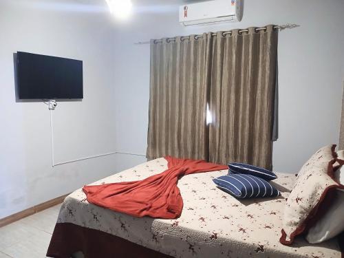 a bedroom with a bed with a television on the wall at CASA COM SPA DE HIDRO, AQUECEDOR E CROMOTERAPIA A 1,0 kM DO CENTRO in Chapada dos Guimarães