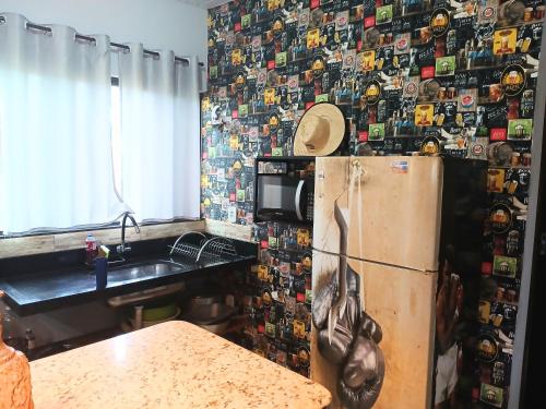 a kitchen with a refrigerator with a wall covered in magnets at CASA COM SPA DE HIDRO, AQUECEDOR E CROMOTERAPIA A 1,0 kM DO CENTRO in Chapada dos Guimarães