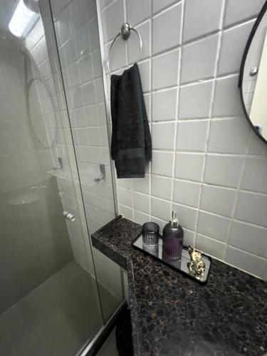 y baño con ducha y toalla negra. en Flat monte castelo condomínio, en Bezerros