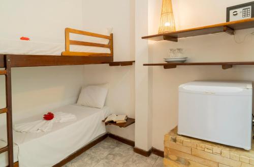 a small room with a bunk bed and a refrigerator at Pousada Villa Tomasi in Jericoacoara