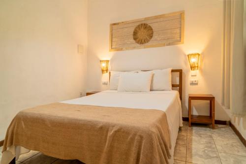 a bedroom with a large white bed with two lamps at Pousada Villa Tomasi in Jericoacoara