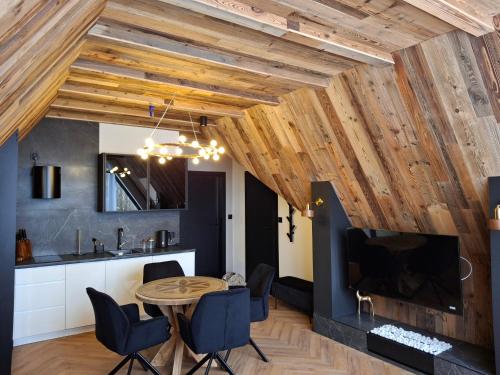 a kitchen and dining room with wooden ceilings and a table and chairs at Zwierzyniecka Residence in Zakopane