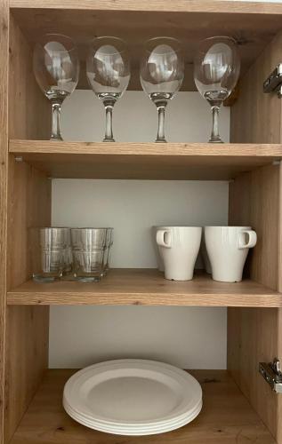 a shelf with wine glasses and bowls on it at Apartament Olesno Centrum in Olesno