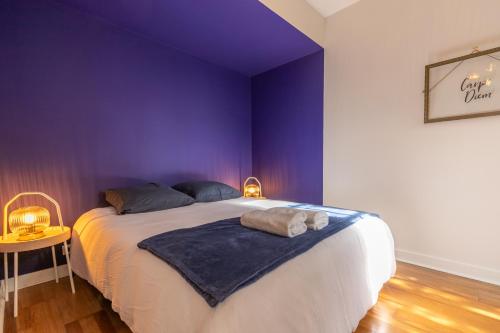 une chambre avec un grand lit aux murs violets dans l'établissement L'Antre des rois - place de parking, à Blois
