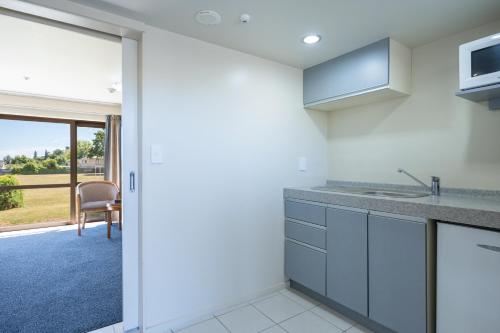 a kitchen with white cabinets and a sliding glass door at Admirals Motor Inn in Nelson